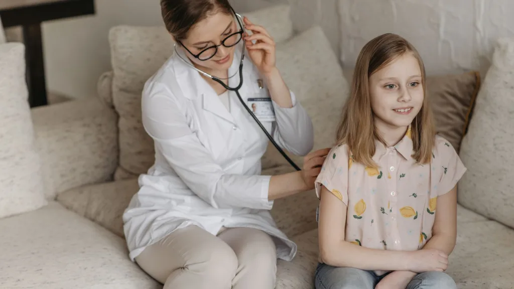 A healthcare professional speaking with a child during a developmental check-up